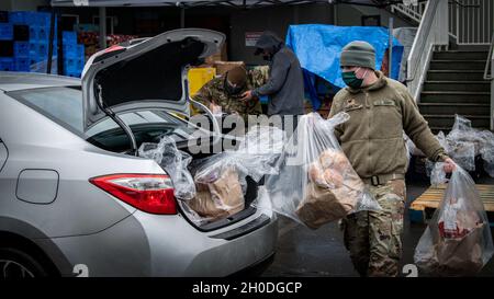 Spc. Bradley Crevling, Ein Unternehmen, 181st Brigade Support Bataillon, lädt ein Lieferwagen des Fahrers, während SPC. Yaquelin Gutierrez 506. Militärpolizei-Abteilung, 96. Truppenkommando, nimmt den Befehl ab, 2. Februar 2021, Kent Wash. Die Lebensmitteldistributionsmission der Washington National Guard kämpft weiterhin gegen den Hunger in Gemeinden, die von den Auswirkungen der COVID-19 schwer getroffen wurden. Stockfoto
