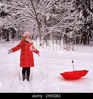 Lächelnde Frau genießt fallenden Schnee, Winterwald mit gefrorenen Bäumen Stockfoto