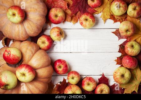 Hintergrund mit Kürbissen, Äpfeln, gefallenen Ahornblättern auf den weißen Holzbrettern Stockfoto