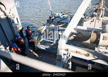 210203-N-RG587-1013 MAYPORT, FL (FEB 3, 2021) Boatswain's Mate Petty Officer 2nd Class Shanita Terry, rechts, zugewiesen an den Ticonderoga-Klasse Lenkraketen-Kreuzer USS Vella Gulf (CG 72), senkt ein starres, aufblasbares Boot (RHIB) ins Wasser 3. Februar 2021. Vella Gulf ist die Pier-Seite an der Naval Station Mayport, die Routinewartung durchführt. Stockfoto