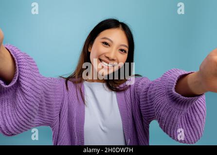 Fotokonzept. Porträt einer asiatischen Frau, die ein Selfie-Bild macht, pov-Aufnahme einer lächelnden Dame Stockfoto