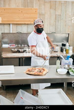 Cook bereitet eine Pizza in einer Restaurantküche zu Stockfoto