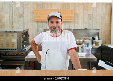 Der Besitzer eines kleinen Restaurants schaut auf die Kamera Stockfoto