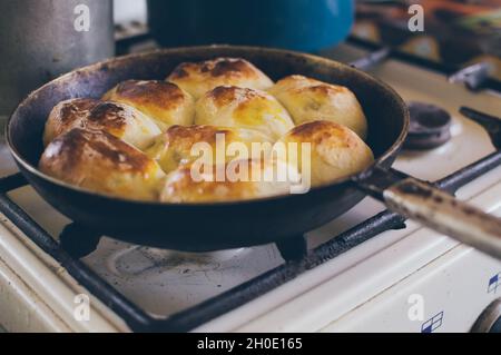 Eine Bratpfanne mit rodig gebackenen Kuchen auf dem Gasherd Stockfoto