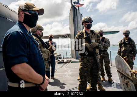 SANTA RITA, Guam (Feb 8, 2021) Matrosen, die dem U-Boot USS Ohio (SSGN 726) der Ohio-Klasse mit Lenkraketen zugewiesen wurden, und Marineinfanteristen, die der 1st Force Reconnaissance Company, III Marine Expeditionary Force, zugewiesen wurden, stehen für eine Übungsübung an der Spitze. Die Übung ist Teil der laufenden Bemühungen von III MEF und der 7. US-Flotte, den regionalen Kommandeuren flexible, vorausschauende und schnelle Reaktionsmöglichkeiten zu bieten. Stockfoto