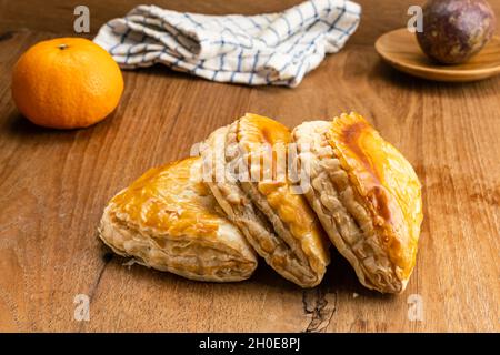 Köstlicher hausgemachter Thunfisch-Kuchen auf Holztisch mit Passionsfrucht in Holzplatte, reifer Orange und Tuch. Stockfoto