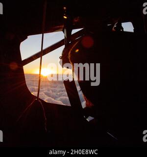 Die Sonne geht auf den Wolken vor dem Cockpitfenster eines KC-135 Stratotankers mit dem 434th Air Betanking Wing von der Grissom Air Reserve Base, Indiana, am 8. Februar 2021 unter. Der Stratotanker wurde an die 927. ARW, Florida, verliehen, aus der die Piloten und der Boombetreiber kamen. Stockfoto