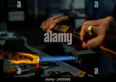 Die Hände eines Flammenarbeiters während der Herstellung von Glasperlen.Diese Kunst wurde 2020 in die repräsentative Liste des immateriellen Kulturerbes aufgenommen Stockfoto