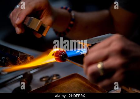 Die Hände eines Flammenarbeiters während der Herstellung von Glasperlen.Diese Kunst wurde 2020 in die repräsentative Liste des immateriellen Kulturerbes aufgenommen Stockfoto