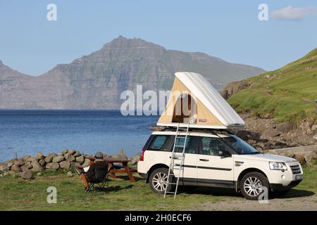 Mann sitzt neben seinem Wohnmobil in Elduvik, Eysturoy Island, Färöer Inseln, Skandinavien, Europa. Stockfoto