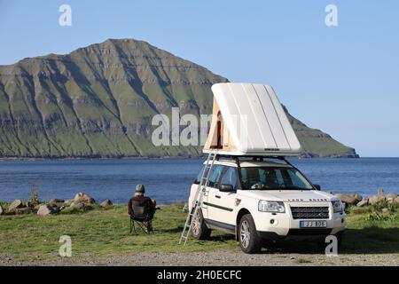 Mann sitzt neben seinem Wohnmobil in Elduvik, Eysturoy Island, Färöer Inseln, Skandinavien, Europa. Stockfoto