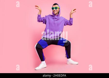 Foto in voller Größe von jungen fröhlichen Mann Hipster haben Spaß verspielte Grimasse isoliert über rosa Hintergrund Stockfoto