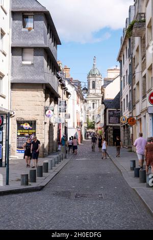 Rennes (Bretagne, Nordwest-Frankreich): Fußgänger in der Rue Saint Melaine im Stadtzentrum und Kirchturm der Kirche Saint Melaine in Stockfoto