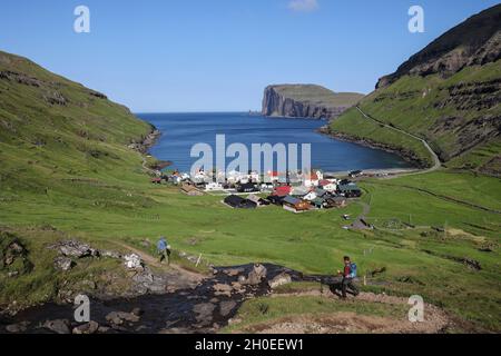 Wanderer gehen einen Hügel hinunter in Richtung des Dorfes Tjornuvik, Streymoy Insel, Färöer Inseln, Skandinavien, Europa Stockfoto