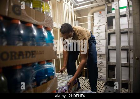 210212-N-RG587-1071 NORFOLK, VA (FEB 12, 2021) Retail Services Specialist Petty Officer 3rd Class James Parker, der dem Ticonderoga-Klasse Lenkraketen-Kreuzer USS Vella Gulf (CG 72) zugeordnet ist, organisiert Geschäfte am 12. Februar 2021. Vella Gulf ist die Pier-Seite der Norfolk Naval Station, die Routinewartung durchführt. Stockfoto