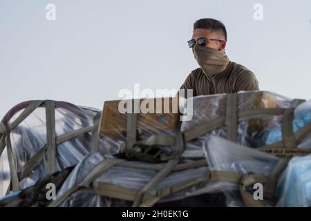 Jamie Ebersole, Senior Airman, 380. Expeditionary Logistics Readiness Squadron, Flugzeugtransportarbeiter, lädt Fracht auf einen C-130 Hercules, der dem 386. Air Expeditionary Wing zugewiesen wurde, während er auf dem Al Dhafra Air Base, Vereinigte Arabische Emirate, am 13. Februar 2021 war. Die Betreuer und Geräte des 380. Air Expeditionary Wings (AEW) wurden zur Al Udeid Air Base in Katar gebracht, um eine integrierte Kampfturn-Übung zu unterstützen. Stockfoto