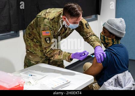 Somerset, N.J., 14. Februar 2021 – Mitarbeiter der FEMA sowie Mitglieder des Verteidigungsministeriums, des NJ EOC und der New Jersey State Troopers unterstützen die COVID-19-Impfung von Gemeindemitgliedern und Mitgliedern der lokalen Gemeinschaft. Ein Mitglied des FEMACorps Team Summit 3 erhält seine erste Impfung. Die FEMA arbeitet mit staatlichen, lokalen, Stammes- und Gebietsregierungen an der kritischen Notwendigkeit, Impfzentren in unterversorgten Gemeinden zu eröffnen. K.C. Wilsey/FEMA Stockfoto