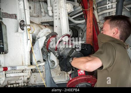 Joe Carter-Blundell, der leitende Flugzeugtechniker der Royal Air Force für einen Tagesteilnehmer, ein Computer-Informationssystemtechniker für den Expeditionary Air Wing 901, verbindet auf der Al Udeid Air Base, Katar, am 16. Februar 2021 eine Kraftstoffleitung an ein Stratotanker-Flugzeug der KC-135. Der Crew-Chef für ein Tagesprogramm bietet direkten Kontakt zu den robusten Luftbetankungskapazitäten des 379. Air Expeditionary Wings. Stockfoto