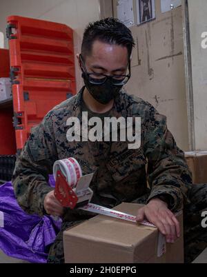 U.S. Marine Corps CPL. Ekin Vang, Postfachangestellter bei Camp Foster Post Office, Marine Corps Installations Pacific, nimmt ein Kundenpaket auf Camp Foster, Okinawa, Japan, 15. Februar 2021 auf. Die Marine Corps Postämter führen ein neues System ein, das es Dienstmitgliedern und ihren Familien ermöglicht, ihre Post schneller zu erhalten. Vang stammt aus Houston, Texas. Stockfoto