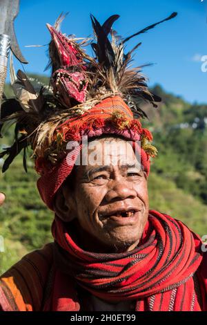 Älterer Ifugao-Mann in traditioneller Tracht. Banaue Reisterrassen im Hintergrund. Banaue, Provinz Ifugao, Philippinen Stockfoto