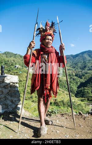 Älterer Ifugao-Mann in traditioneller Tracht. Banaue Reisterrassen im Hintergrund. Banaue, Provinz Ifugao, Philippinen Stockfoto