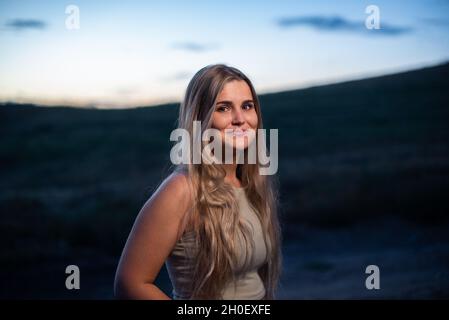 Porträt einer blonden kaukasischen Frau, die lächelt, während es dunkel wird Stockfoto