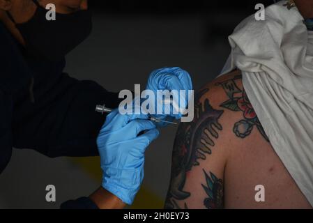Mitglieder der Küstenwache nehmen freiwillig den COVID-19-Impfstoff im Rahmen der Operation Honey Bee in San Diego, Februar 18, ein. 2021. Für die Operation Honey Bee verwendete die Küstenwache ein Spartan-Flugzeug C-27, um den Impfstoff mit den Küstenwache-Mitarbeitern in Los Angeles, San Diego und Seattle zu transportieren und zu teilen, was die Anzahl der Männer und Frauen der Küstenwache, die geimpft werden können, stark erhöhte. Stockfoto