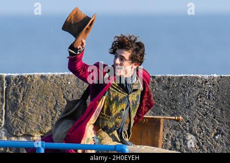 Lyme Regis, Dorset, Großbritannien. Oktober 2021. Szenen für den neuen Wonka-Film mit Timothée Chalamet, der heute Nachmittag im Hafen von Cobb bei Lyme Regis in Dorset gedreht wird. Timothée Chalamet, der den jungen Willy Wonka spielt, wird auf einem Van-Dach reiten sehen. Bildnachweis: Graham Hunt/Alamy Live News Stockfoto