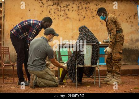 Ein First-Class-Sergeant der US-Armee, der der 3. Special Forces Group (Airborne) zugewiesen wurde, arbeitet mit einem Soldaten der Armee von Burkina Faso zusammen, um einem Burkinabé-Ortsansässigen in Bobo-Dioulasso, Burkina Faso, medizinische Hilfe zu leisten, 18. Februar 2021. Civil Affairs Team 142, D/Co, 91. CA BN stellte medizinische Geräte und Schulungen für burkinabé Militärärzte in Bobo-Dioulasso zur Verfügung. Die Ausbildung unterstützte die medizinischen Untersuchungen und Behandlungen von mehr als 400 Menschen mit der US-Militärhilfe, die sich auf den Aufbau der Kapazitäten der Sicherheitskräfte Burkina Fasos konzentrierte. Stockfoto