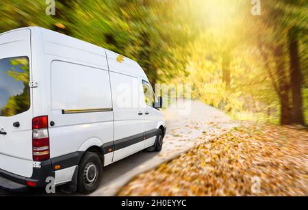 Weißer Lieferwagen auf einer Landstraße im Herbst Stockfoto