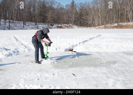 210219-N-AP176-1026 LITTLE FALLS, Minn. - (Feb 19, 2021) Navy Diver 3rd Class Joshua Hafler, zugeordnet zu Mobile Diving and Salvage Unit (MDSU) 2 verwendet eine Schnecke, um während des Eistauchtrainings im Camp Ripley in Little Falls, Minn, ein Taucheintrittsloch zu schneiden. Das Training, das von MDSU 2, Befindet sich in der dritten Auflage und wurde relevanter, was zeigt, wie Taucher der Marine beim Aufbau einer leistungsfähigeren arktischen Seestreitkräfte helfen. MDSU 2, gegründet von der Joint Expeditionary Base Little Creek - Fort Story, ist eine kampfbereite Expeditionstruppe, die weltweit zur Unterstützung aller Tauchgänge eingesetzt werden kann Stockfoto