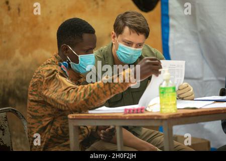 Ein First Class-Sergeant der US-Armee, der der 3. Special Forces Group (Airborne) zugewiesen wurde, arbeitet mit einem Soldaten der Armee von Burkina Faso zusammen, um einem burkinabé-Bürger in Bobo-Dioulasso, Burkina Faso, medizinische Hilfe zu leisten, 19. Februar 2021. Civil Affairs Team 142, D/Co, 91. CA BN stellte medizinische Geräte und Schulungen für burkinabé Militärärzte in Bobo-Dioulasso zur Verfügung. Die Ausbildung unterstützte die medizinischen Untersuchungen und Behandlungen von mehr als 400 Menschen mit der US-Militärhilfe, die sich auf den Aufbau der Kapazitäten der Sicherheitskräfte Burkina Fasos konzentrierte. Stockfoto