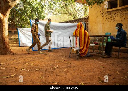 Ein First Class-Sergeant der US-Armee, der der 3. Special Forces Group (Airborne) zugewiesen wurde, arbeitet mit einem Soldaten der Armee von Burkina Faso zusammen, um einem burkinabé-Bürger in Bobo-Dioulasso, Burkina Faso, medizinische Hilfe zu leisten, 19. Februar 2021. Civil Affairs Team 142, D/Co, 91. CA BN stellte medizinische Geräte und Schulungen für burkinabé Militärärzte in Bobo-Dioulasso zur Verfügung. Die Ausbildung unterstützte die medizinischen Untersuchungen und Behandlungen von mehr als 400 Menschen mit der US-Militärhilfe, die sich auf den Aufbau der Kapazitäten der Sicherheitskräfte Burkina Fasos konzentrierte. Stockfoto