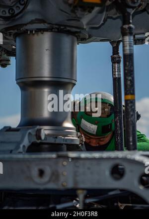 PAZIFISCHER OZEAN (Feb 20, 2021) U.S. Navy Aviation Structural Mechanic 2nd Class James Han, aus Tian Jin, China, zugewiesen an die „Magier“ des Helicopter Maritime Strike Squadron (HSM) 35, blutet die Rotorbremse auf einem MH-60R Sea Hawk auf dem Flugdeck des Arleigh Burke-Klasse Lenkraketen-Zerstörers USS John Finn (DDG 113) Februar 20, 2021. John Finn, Teil der Theodore Roosevelt Carrier Strike Group, ist im geplanten Einsatzgebiet der 7. US-Flotte unterwegs. Da die US-Navy die größte vorwärtseingesetzte Flotte ist, arbeitet die 7. Flotte routinemäßig mit 35 maritimen Nationen zusammen und interagiert mit ihr Stockfoto