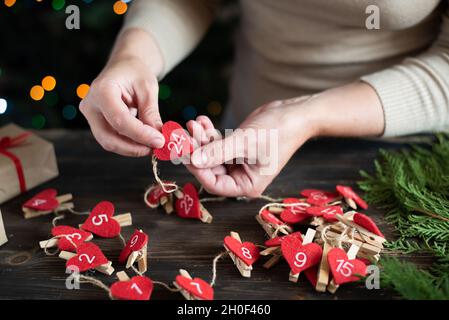 Frau macht einen Adventskalender für ihr Kind, Vorbereitung auf Weihnachten, Urlaub DIY Crafting, close-up. Stockfoto