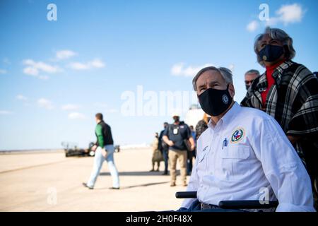 Der Gouverneur von Texas, Greg Abbott, beobachtet, wie Airmen mit dem 502. Logistics Readiness Squadron bei der Koordination und dem Entladen von etwa 80,000 Wasserflaschen hilft, die über Flugzeuge auf dem Kelly Field in die Stadt San Antonio gebracht werden, nachdem der Wintersturm Uri, 21. Februar 2021, Am Joint Base San Antonio-Kelly Field, Texas. Stockfoto