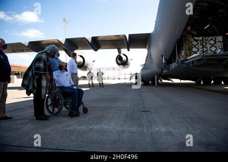 Der Gouverneur von Texas, Greg Abbott (links), beobachtet, wie Airmen mit dem 502. Logistics Readiness Squadron bei der Koordination und dem Entladen von ca. 80,000 Wasserflaschen hilft, die über Flugzeuge auf dem Kelly Field in die Stadt San Antonio gebracht werden, nachdem der Wintersturm Uri, 21. Februar 2021, Am Joint Base San Antonio-Kelly Field, Texas. Stockfoto