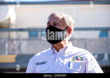 Der Gouverneur von Texas, Greg Abbott, beobachtet, wie Airmen mit dem 502. Logistics Readiness Squadron bei der Koordination und dem Entladen von etwa 80,000 Wasserflaschen hilft, die über Flugzeuge auf dem Kelly Field in die Stadt San Antonio gebracht werden, nachdem der Wintersturm Uri, 21. Februar 2021, Am Joint Base San Antonio-Kelly Field, Texas. Stockfoto