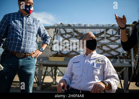 Der Gouverneur von Texas, Greg Abbott (Mitte), beobachtet, wie Airmen mit dem 502. Logistics Readiness Squadron bei der Koordination und dem Entladen von ca. 80,000 Wasserflaschen hilft, die über Flugzeuge auf dem Kelly Field in die Stadt San Antonio gebracht werden, nachdem der Wintersturm Uri, 21. Februar 2021, Am Joint Base San Antonio-Kelly Field, Texas. Stockfoto