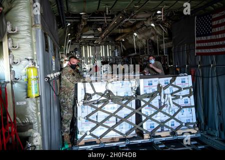 Die US Air Force Airmen unterstützen die Koordination und das Entladen von abgefülltem Wasser auf einer C-130 vom 136. Airlift Wing, Texas Air National Guard, Ft. Worth, 21. Februar 2021, bei der Joint Base San Antonio-Kelly Field, Texas. Das 502. Logistics Readiness Squadron unterstützte die Koordination und das Entladen von etwa 80,000 Flaschen Wasser, die über Flugzeuge auf dem Kelly Field eingeliefert wurden und nach dem Wintersturm Uri an die Stadt San Antonio verteilt werden sollten. Stockfoto