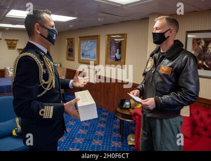 Der italienische Marinehafter Gianfranco Vizzini, Marinehandtaché, links, überreicht ein Geschenk an den US-Marinehafter Cassidy Norman, Kommandeur des Flugzeugträgers USS John C. Stennis (CVN 74), im Namen des italienischen Marinehafters Giancarlo Ciappina, Kommandeur des Flugzeugträgers ITS Cavour (CVH 550), In der Kajüte des Kapitäns an Bord der USS John C. Stennis, in Norfolk, Virginia, 22. Februar 2021. John C. Stennis arbeitet mit Newport News Shipbuilding zusammen, um die Überholung des Tankkomplexes planmäßig mit einer geschulten, widerstandsfähigen und geschlossenen Crew abzuschließen. Stockfoto