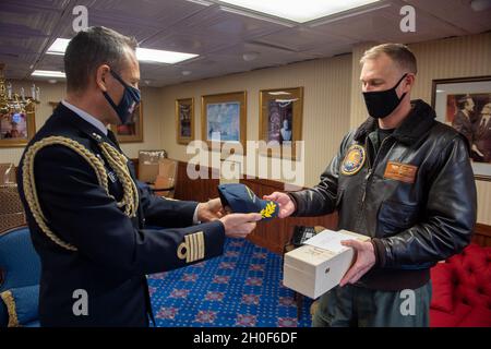 Der italienische Marinehafter Gianfranco Vizzini, Marinehandtaché, links, überreicht ein Geschenk an den US-Marinehafter Cassidy Norman, Kommandeur des Flugzeugträgers USS John C. Stennis (CVN 74), im Namen des italienischen Marinehafters Giancarlo Ciappina, Kommandeur des Flugzeugträgers ITS Cavour (CVH 550), In der Kajüte des Kapitäns an Bord der John C. Stennis, in Norfolk, Virginia, 22. Februar 2021. John C. Stennis arbeitet mit Newport News Shipbuilding zusammen, um die Überholung des Tankkomplexes planmäßig mit einer geschulten, widerstandsfähigen und geschlossenen Crew abzuschließen. Stockfoto