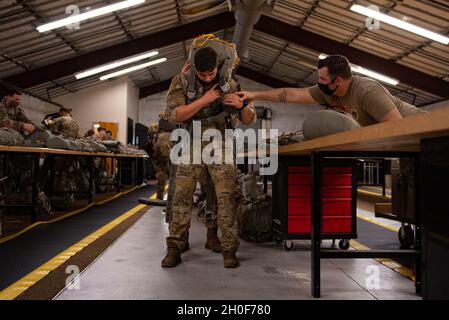 Ein der 820. Base Defence Group zugewiesener Flieger erhält Hilfe, während er vor einem Luftsprung für Mosaic Tiger am 22. Februar 2021 auf der Moody Air Force Base, Georgia, einen Fallschirm anlegt. Luftinfiltrationsoperationen führten zu einer Flugplatzsicherheit und einer sicheren Ankunft von Folgekräften für Mosaic Tiger. Mosaic Tiger wurde entwickelt, um die Fähigkeit des 23d Wings zu testen, multifähige Airmen in gemeinsame Operationen zu integrieren und dabei eine leichtere Abstandsfläche im Downrange beizubehalten. Stockfoto