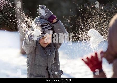 Junge und Mädchen spielen Schneeballschlacht am kalten Wintertag im Park Stockfoto