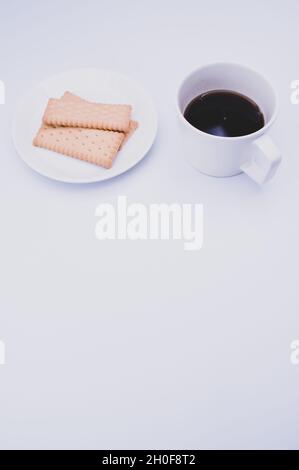 tasse schwarzen Kaffee und leichte, knackige Kekse auf einem weißen Teller Stockfoto