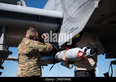 Personal Sgt. Brannon House, 74th Aircraft Maintenance Unit Weapons load Crew Chief, Left, and Airman First Class Steven Mulonet, 74th Aircraft Maintenance Unit Weapons load Crew member, befestigen Sie eine Übungsbombe auf einem A-10C Thunderbolt II während Mosaic Tiger 21-1, 23. Februar 2021, auf der Moody Air Force Base, Georgia. Mosaic Tiger 21-1 war die erste agile Kampfübung des 23d-Flügels, bei der sie als Führungsflügel für etwa 800 Luftwaffe von sieben Flügeln in vier Hauptkommandos fungierten. Das 23d Wing Integration and Training Office testete den Einsatz von multifähigen Airmen, einem neuen Stockfoto