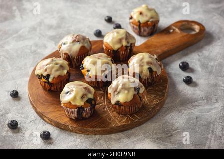 Hausgemachte Muffins mit roten Johannisbeeren und Blaubeeren, bedeckt mit weißer Schokolade. Stockfoto