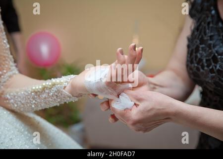 Die Braut legt ihr das Taschentuch in die Hände. Die Hand der Braut ist am Bogen befestigt Stockfoto