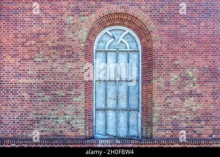 Gewölbtes Fenster, das sich mit einem alten Holzrahmen auf dem Hintergrund einer alten roten Backsteinmauer öffnet. Aus der Serie Windows of the World. Stockfoto