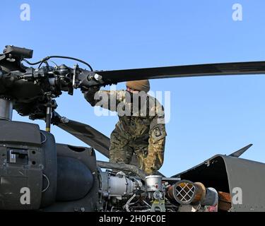 Spc. Daveyon Adkins mit Charlie Company 'Bavarian DUSTOFF', 1. Bataillon, 214. Luftfahrtregiment, 12. Kampfluftfahrtbrigade, setzt die Vorflugkontrollen fort und überprüft den allgemeinen Zustand und die Sicherheit der Hauptrotornabe und der Hauptrotorblätter, Baumholder Manöver Training Area, Deutschland, 24. Februar 2021. Stockfoto